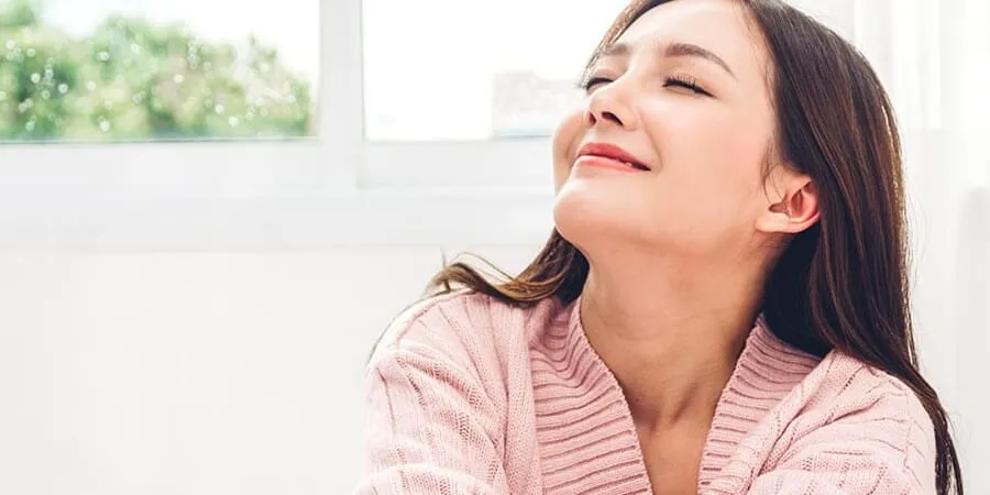 woman smiling breathing in the fresh air in her home